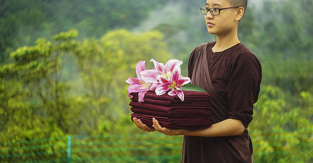 Buddhistischer Mönch mit Gewändern im Arm
